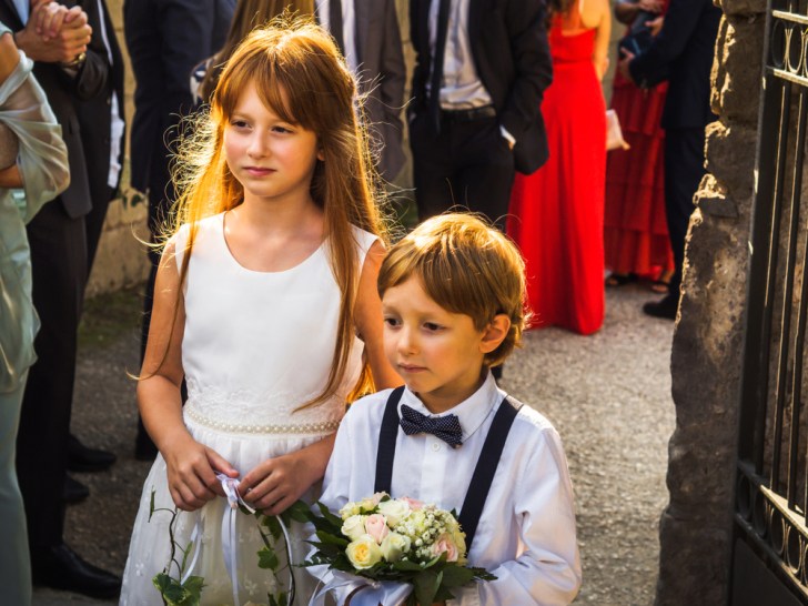 Ring bearer and flower girl at summer wedding near church. Italy