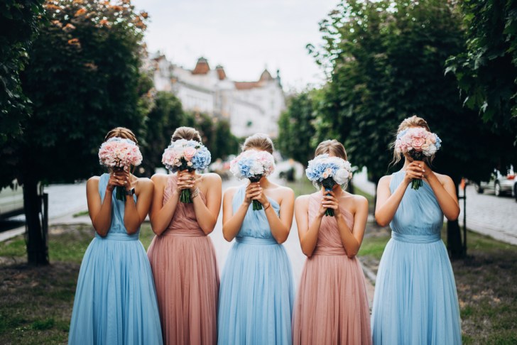 Bridesmaids at wedding with bouquets in hands. Girl in colored dresses for wedding.