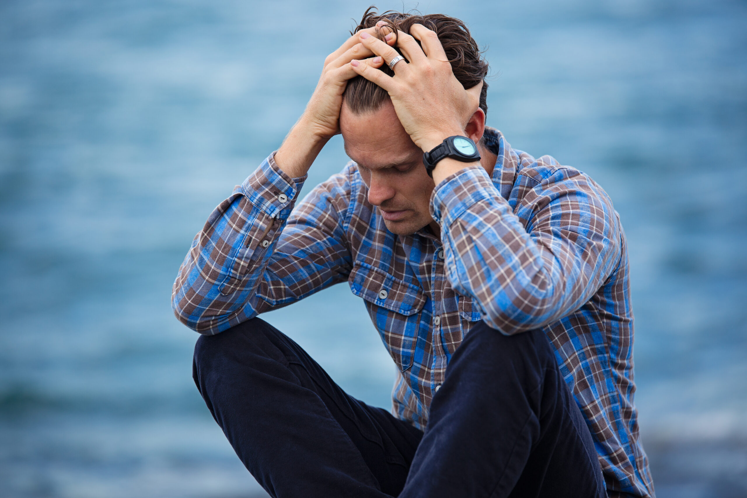 Man in blue and brown plaid dress shirt touching his hair