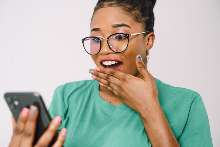 Shocked woman in glasses looking at cellphone screen