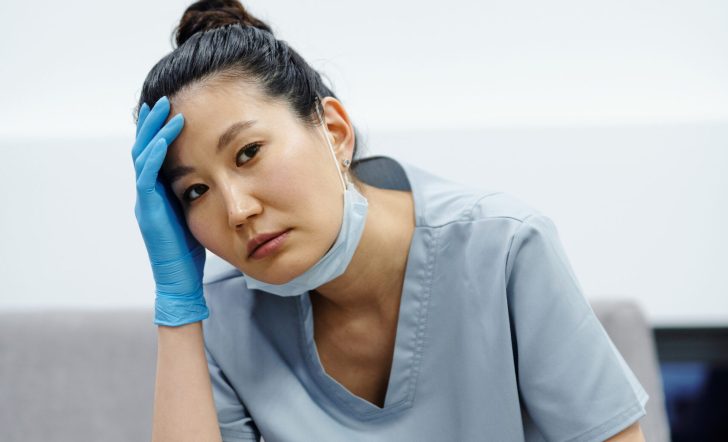 A woman in scrub suit holding her head