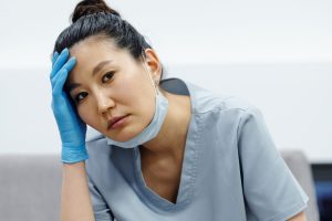 A woman in scrub suit holding her head